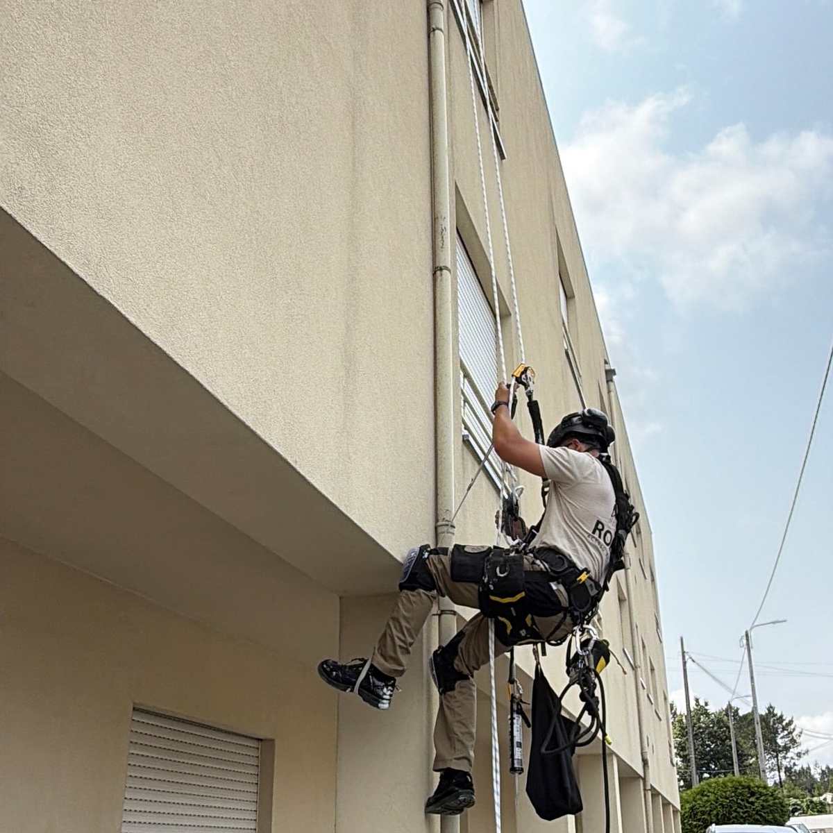 Trabalho em altura numa fachada, com o edifício e o céu em fundo