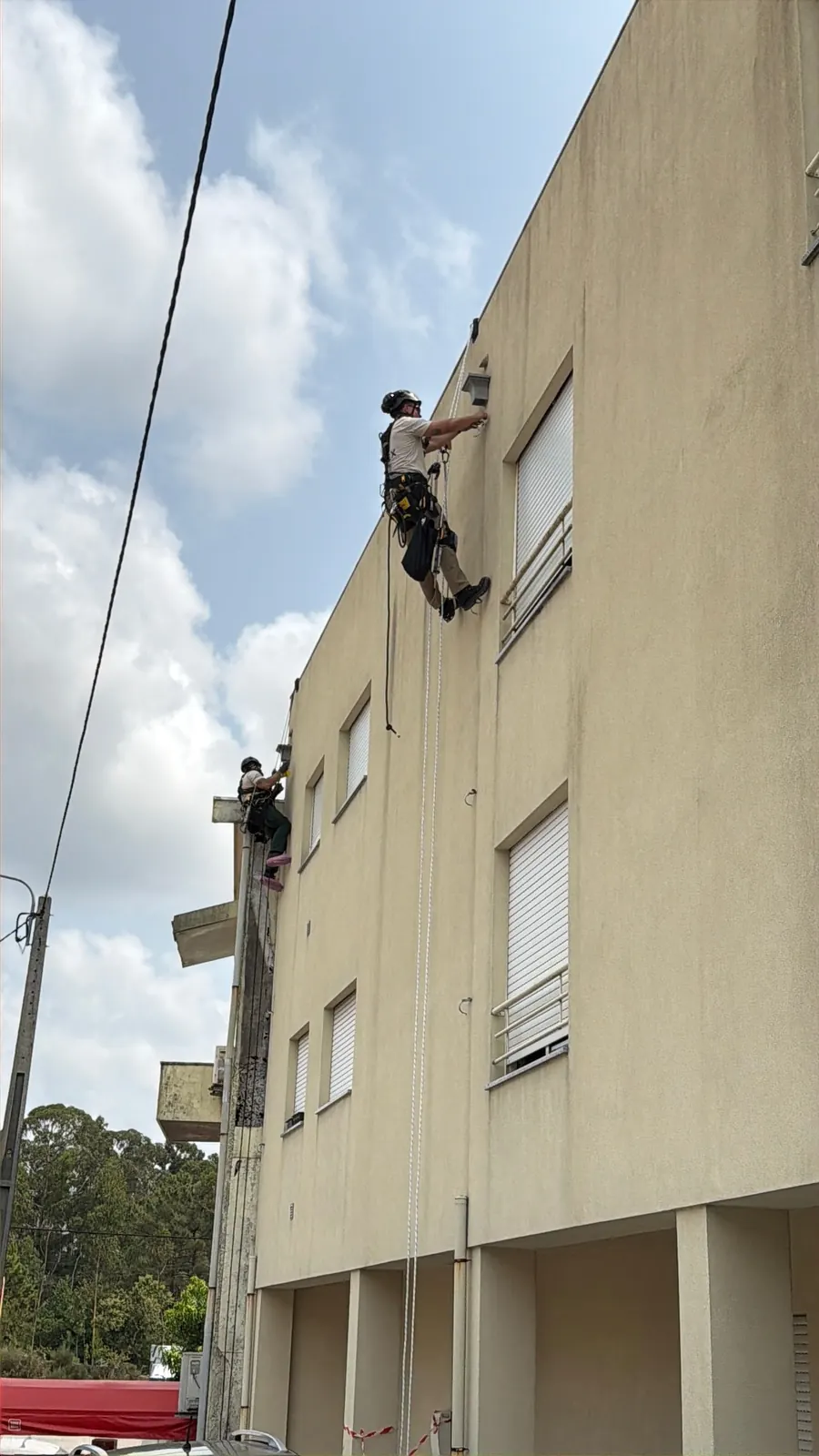 Dois técnicos da RopeX suspensos em pontos diferentes da fachada do mesmo edifício