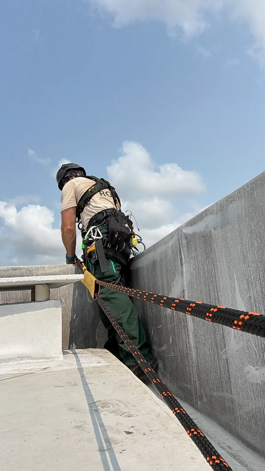 Técnico da RopeX junto à platibanda, com as duas cordas estendidas pela cobertura até ao lado de fora do edifício