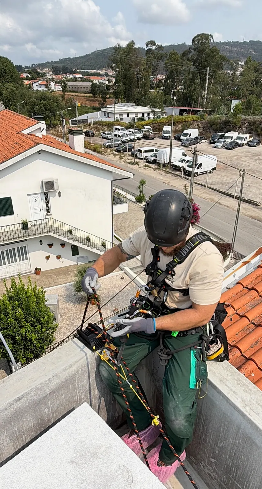 Técnico da RopeX na platibanda a passar a corda pelo descensor antes da descida, com a rua lá em baixo