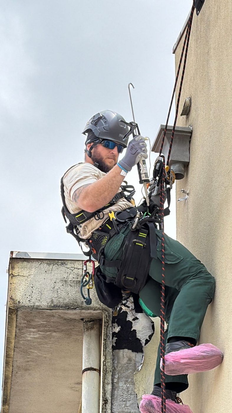 Técnico da RopeX suspenso em duas linhas independentes a aplicar vedante numa fachada