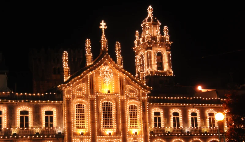 Fachada de igreja e arcada em Braga totalmente contornadas por lâmpadas de luz quente